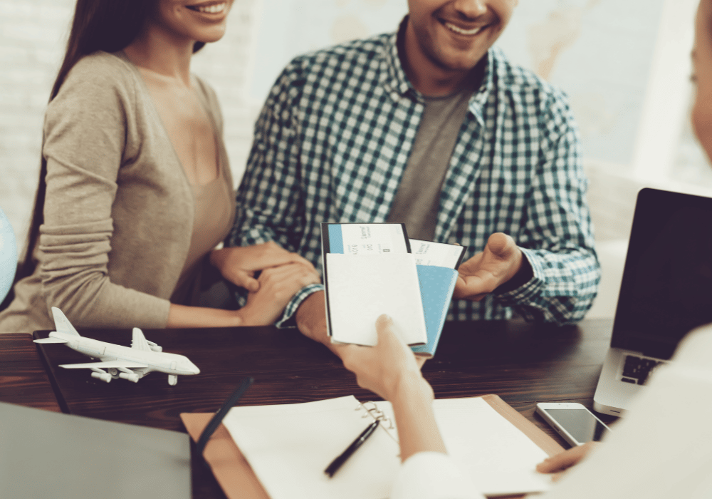 agent de voyage en train de donner des billets d'avion à un couple